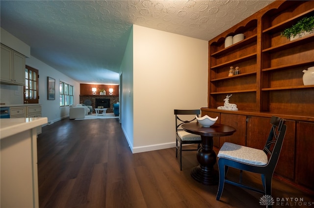living area with dark wood-style floors, baseboards, a textured ceiling, and a fireplace