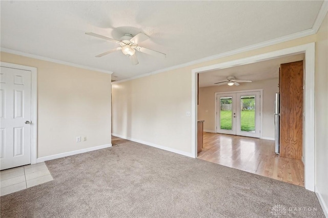 carpeted empty room featuring french doors, ceiling fan, baseboards, and ornamental molding
