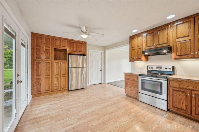 kitchen featuring stainless steel appliances, under cabinet range hood, light wood-type flooring, brown cabinets, and recessed lighting