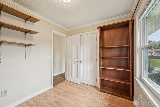 unfurnished bedroom with light wood finished floors, multiple windows, crown molding, a textured ceiling, and baseboards