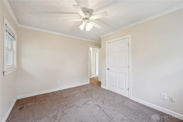 unfurnished bedroom featuring carpet floors, ornamental molding, baseboards, a textured ceiling, and a ceiling fan