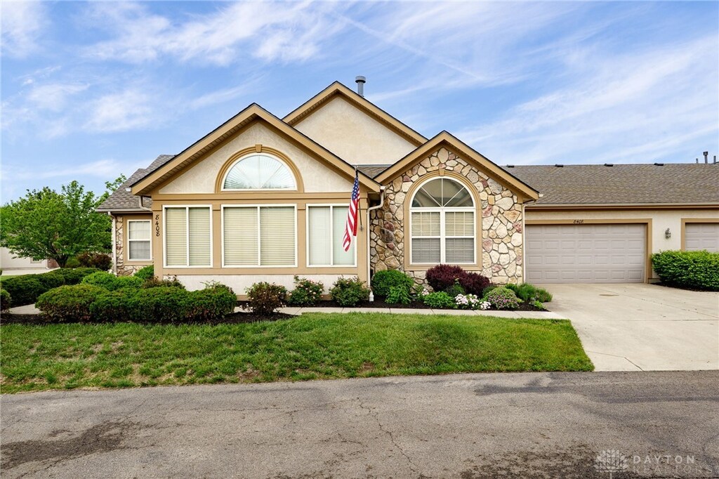 8408 Royal Birkdale Dr, Dayton, OH 45458 - single story home featuring stone siding, concrete driveway, a garage, stucco siding, and a front lawn