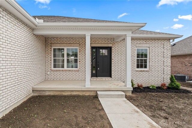 755 W Bentley Cir, Troy, OH 45373 - doorway to property featuring a porch, brick siding, a shingled roof, and central AC