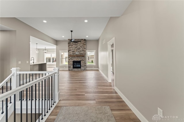 755 W Bentley Cir, Troy, OH 45373 - unfurnished living room with ceiling fan, wood finished floors, a stone fireplace, baseboards, and recessed lighting