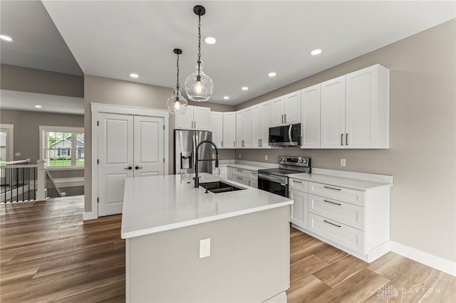 755 W Bentley Cir, Troy, OH 45373 - kitchen featuring appliances with stainless steel finishes, a sink, wood finished floors, light countertops, and white cabinetry