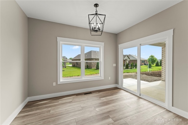 755 W Bentley Cir, Troy, OH 45373 - unfurnished dining area with healthy amount of natural light, a chandelier, light wood finished floors, and baseboards