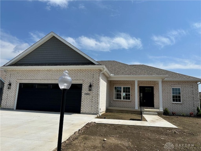 755 W Bentley Cir, Troy, OH 45373 - view of front of house with a garage, brick siding, concrete driveway, roof with shingles, and covered porch