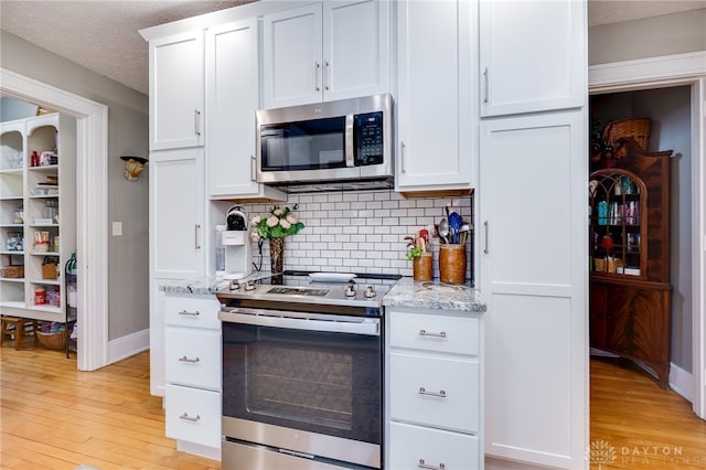 65 N Central Ave, Fairborn, OH 45324 - kitchen with appliances with stainless steel finishes, light wood-type flooring, decorative backsplash, white cabinets, and light stone countertops