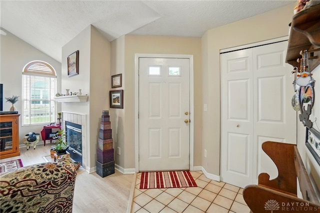 foyer featuring a fireplace, lofted ceiling, and baseboards