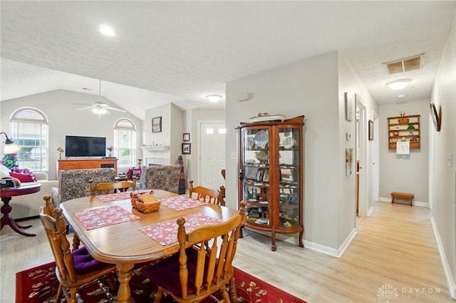 dining room with light wood-style flooring, ceiling fan, lofted ceiling, and baseboards