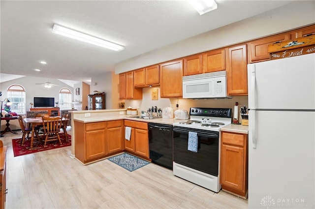 kitchen with white appliances, a peninsula, a sink, light wood-style floors, and light countertops