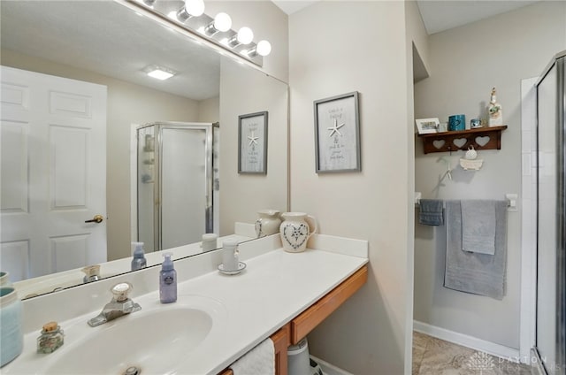 bathroom featuring a stall shower, vanity, and baseboards
