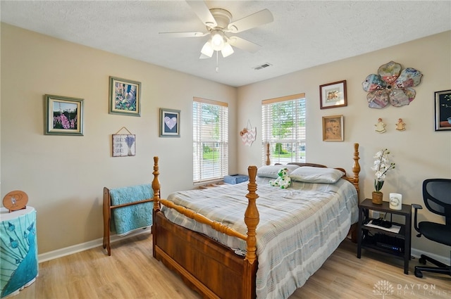 bedroom featuring light wood finished floors, baseboards, a textured ceiling, and a ceiling fan