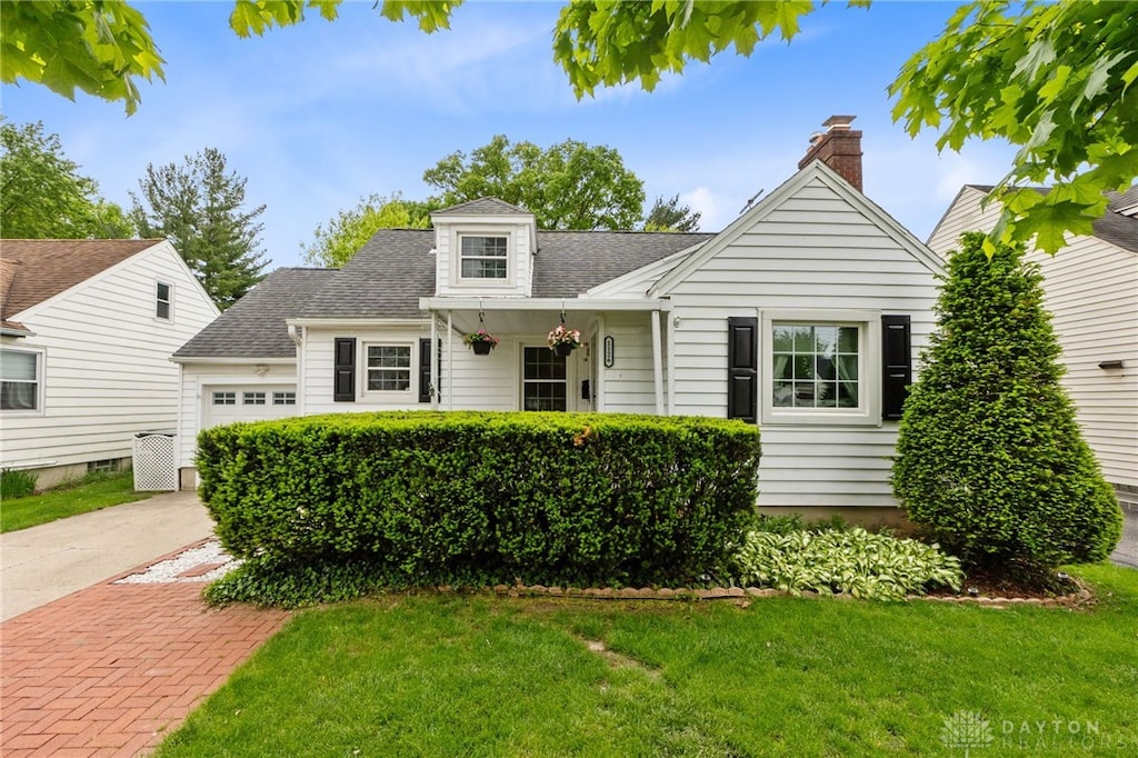 1126 Patterson Rd, Dayton, OH 45420 - cape cod home featuring an attached garage, a front yard, roof with shingles, a chimney, and driveway