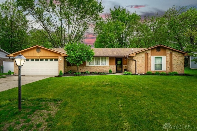 ranch-style home with an attached garage, concrete driveway, a front lawn, and brick siding