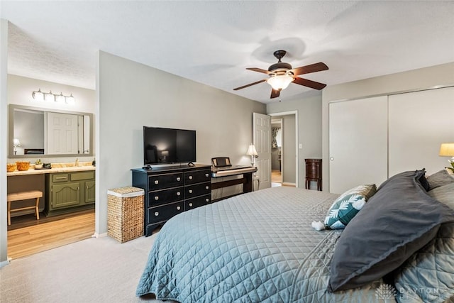 bedroom featuring a closet, a sink, light carpet, connected bathroom, and a ceiling fan