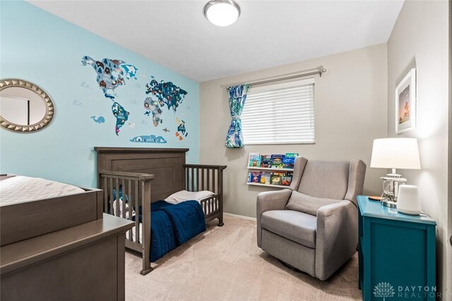 bedroom with light colored carpet, baseboards, and a crib