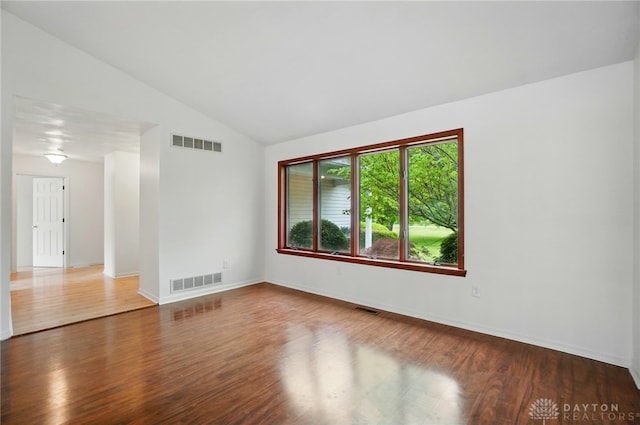 spare room featuring lofted ceiling, wood finished floors, and baseboards