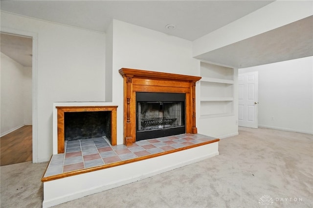 unfurnished living room with a tile fireplace, carpet flooring, baseboards, and built in features