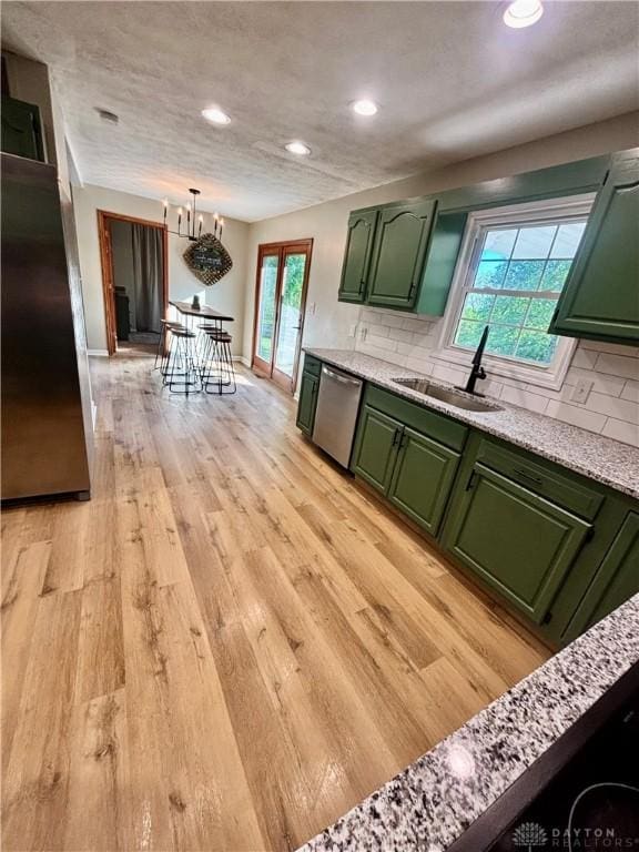 kitchen with green cabinets, a sink, stainless steel dishwasher, recessed lighting, and backsplash