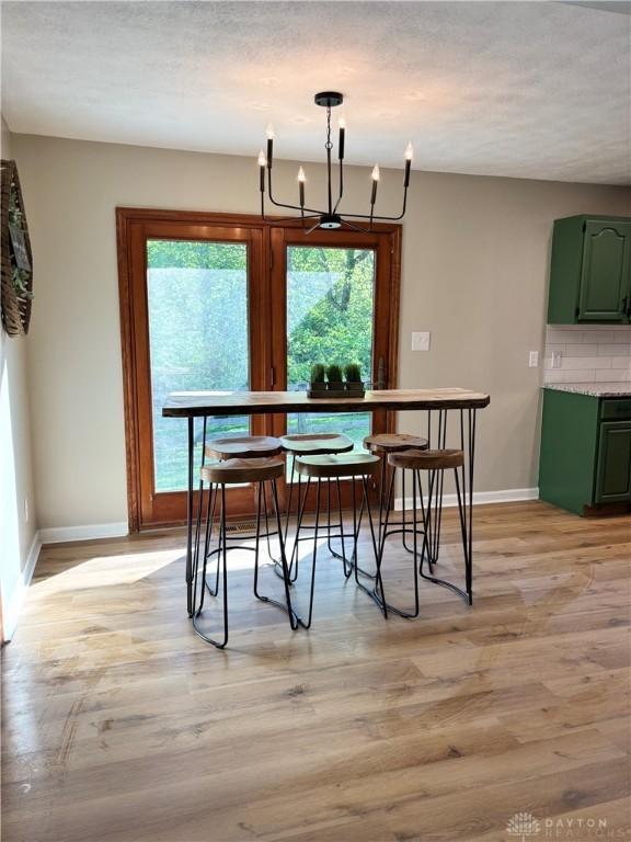dining area with baseboards, light wood finished floors, plenty of natural light, and a chandelier