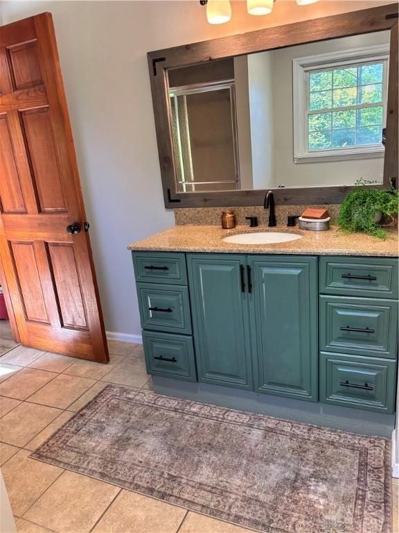 full bath with vanity, a stall shower, tile patterned flooring, and baseboards