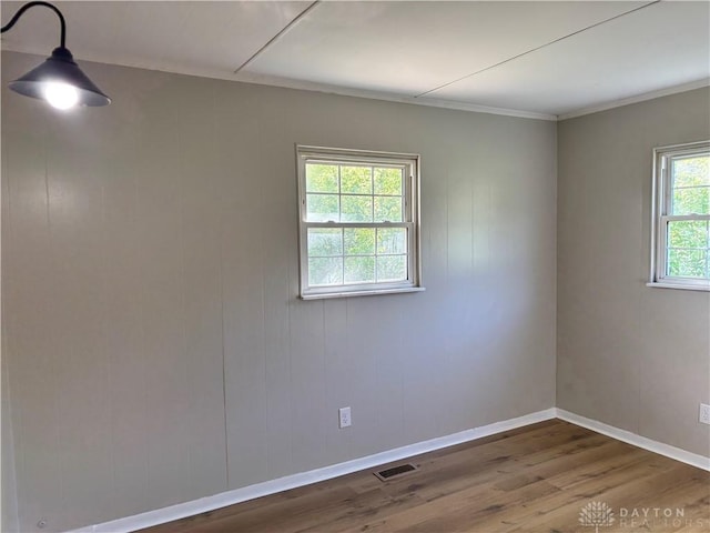 unfurnished room featuring dark wood-type flooring, baseboards, and crown molding
