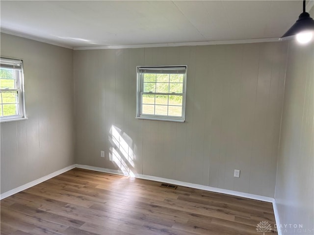 unfurnished room featuring wood finished floors, baseboards, and ornamental molding