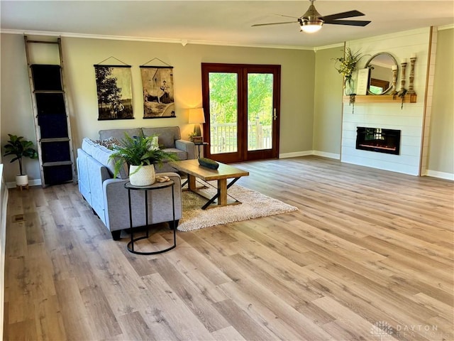 living area featuring ceiling fan, wood finished floors, crown molding, and baseboards