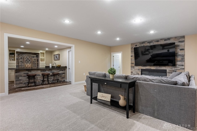 carpeted living room with wet bar, recessed lighting, baseboards, and a fireplace