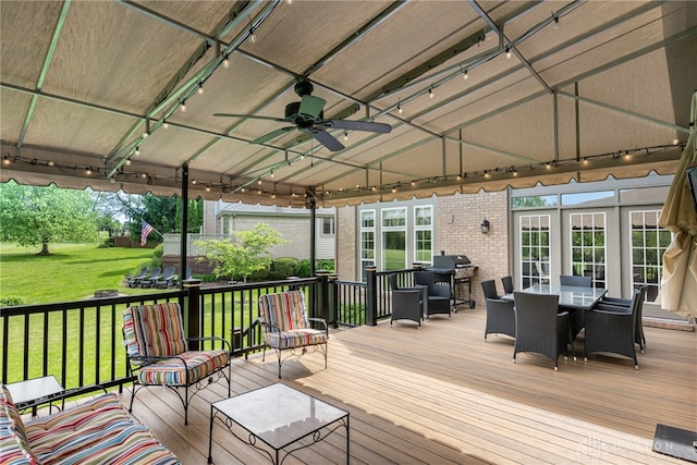 wooden deck featuring outdoor dining space, ceiling fan, and a yard