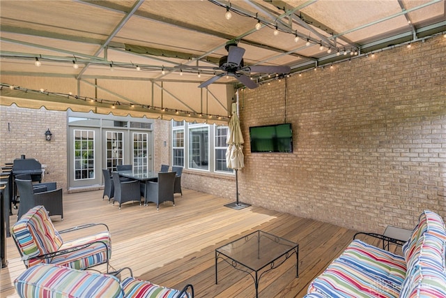 wooden deck with outdoor dining space, a ceiling fan, and french doors
