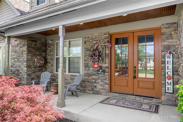 entrance to property featuring stone siding, covered porch, and french doors