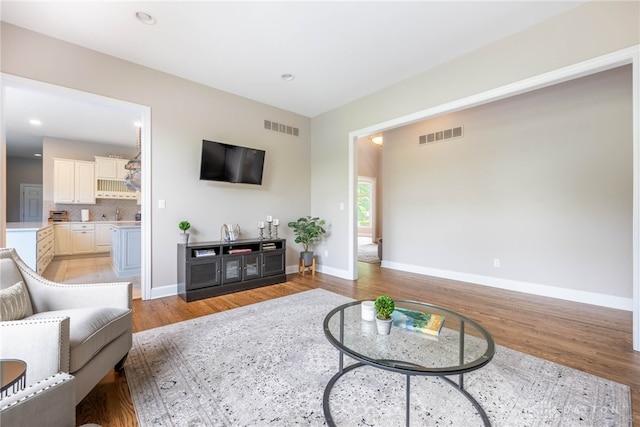 living area with light wood-type flooring, baseboards, and recessed lighting