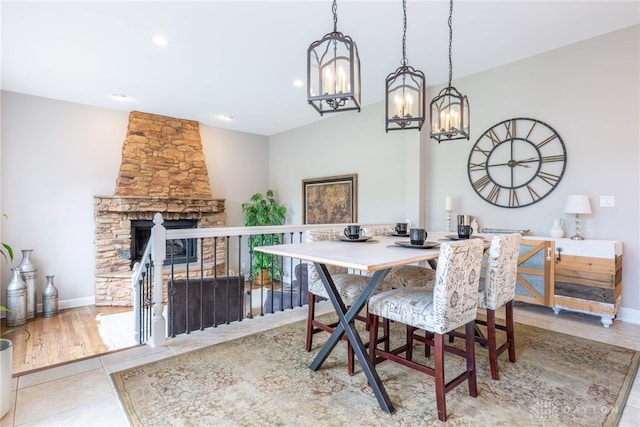 tiled dining room featuring a chandelier, a stone fireplace, baseboards, and recessed lighting