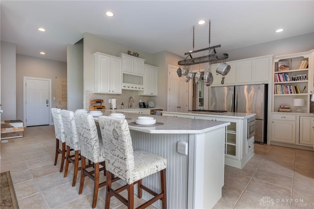 kitchen with a center island, light tile patterned floors, tasteful backsplash, light countertops, and a breakfast bar