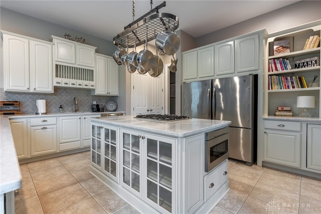 kitchen with stainless steel appliances, glass insert cabinets, tasteful backsplash, and white cabinets