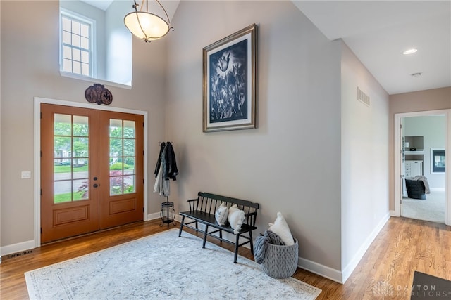 foyer entrance featuring french doors, wood finished floors, baseboards, and a high ceiling