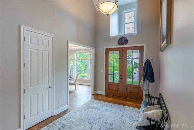 entryway with french doors, wood finished floors, baseboards, and a towering ceiling