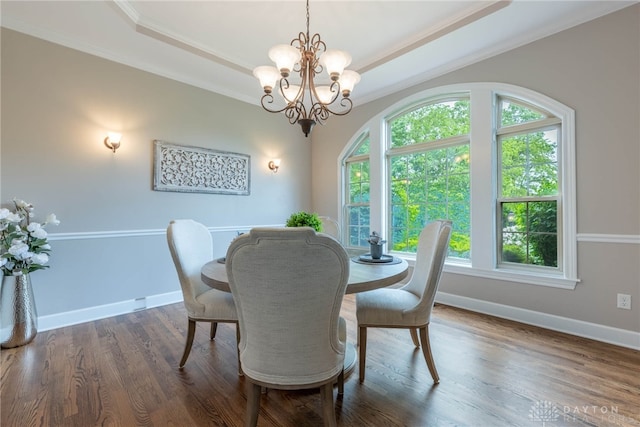 dining area featuring a tray ceiling, a chandelier, ornamental molding, baseboards, and wood finished floors