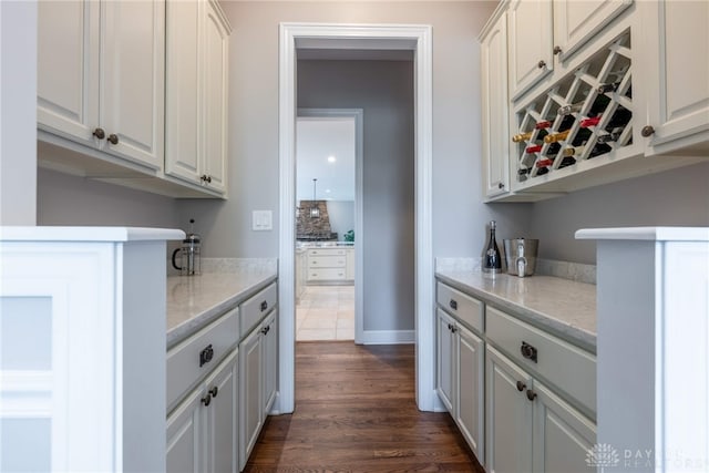 kitchen featuring dark wood-style flooring, white cabinetry, and light stone countertops