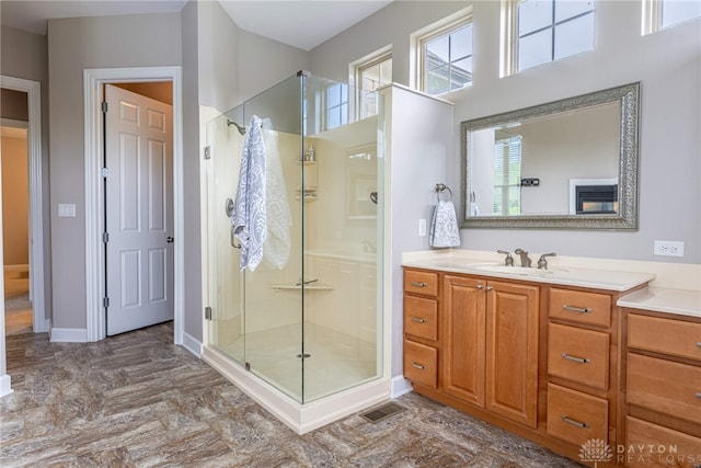 bathroom with a stall shower, vanity, and baseboards