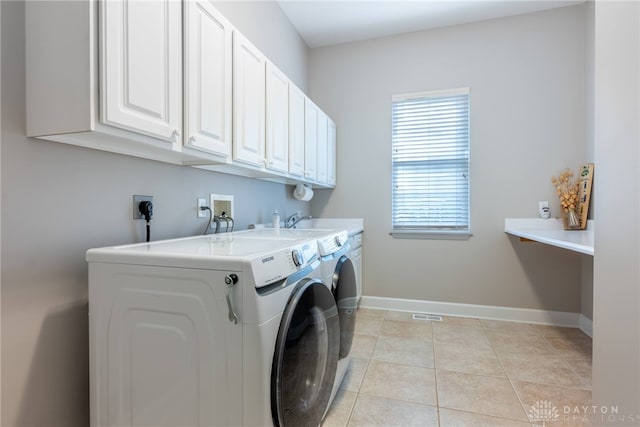 clothes washing area featuring cabinet space, separate washer and dryer, baseboards, and light tile patterned floors