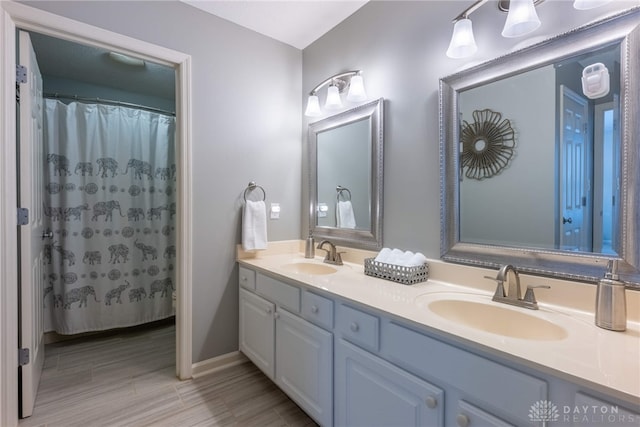 full bath featuring double vanity and baseboards