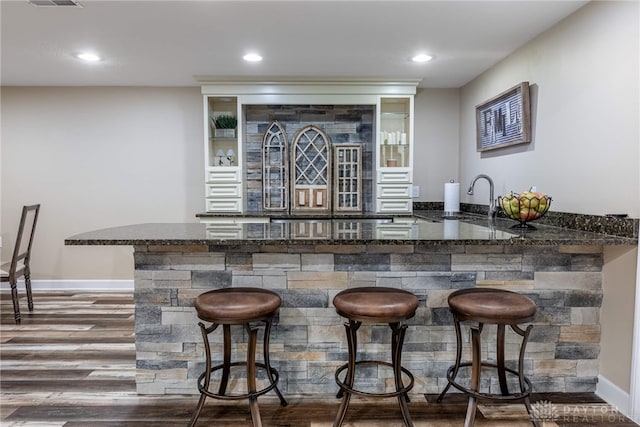 indoor wet bar featuring wood finished floors, baseboards, and recessed lighting