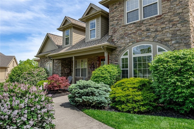 property entrance with stone siding and a shingled roof