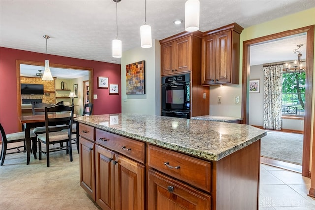 2100 Hunters Bluff Ct, Washington Twp, OH 45458 - kitchen featuring hanging light fixtures, light stone counters, brown cabinetry, light tile patterned floors, and a kitchen island