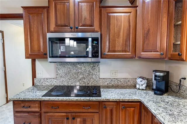 2100 Hunters Bluff Ct, Washington Twp, OH 45458 - kitchen featuring stainless steel microwave, black electric stovetop, brown cabinetry, and light stone counters