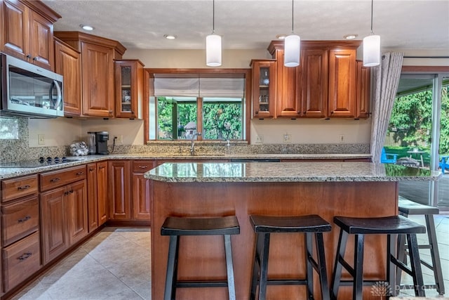 2100 Hunters Bluff Ct, Washington Twp, OH 45458 - kitchen with stainless steel microwave, a sink, brown cabinetry, a breakfast bar area, and recessed lighting