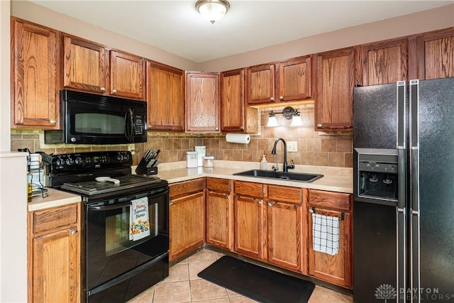 kitchen featuring black appliances, a sink, light countertops, and brown cabinetry